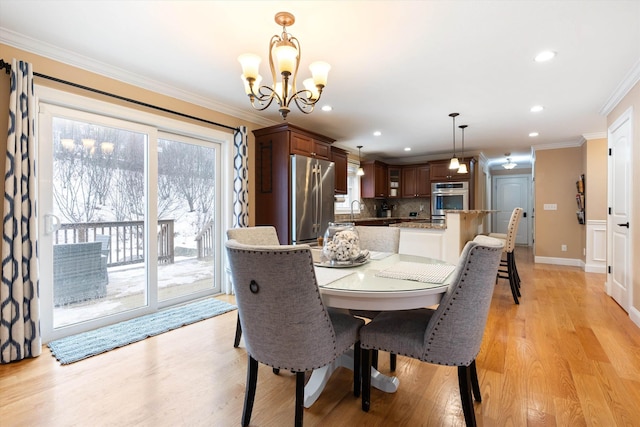 dining room with an inviting chandelier, sink, light hardwood / wood-style flooring, and ornamental molding