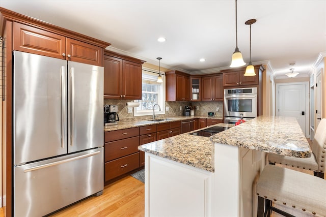 kitchen with stainless steel appliances, sink, pendant lighting, and a breakfast bar