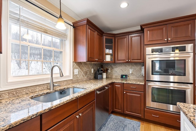 kitchen featuring pendant lighting, sink, stainless steel appliances, light stone counters, and tasteful backsplash