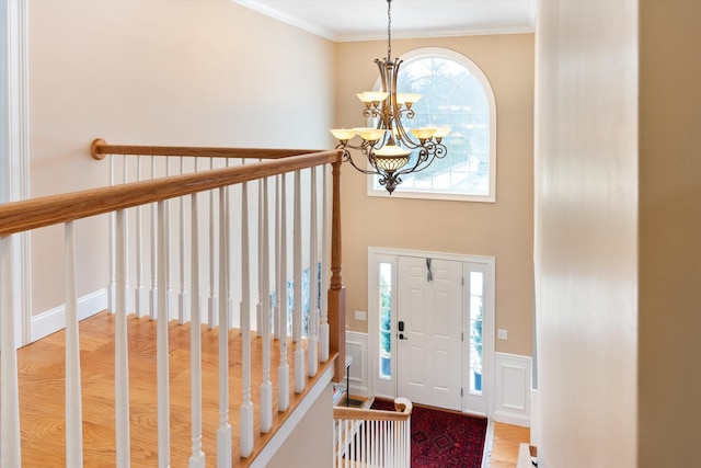 entrance foyer with crown molding, wood-type flooring, and a notable chandelier