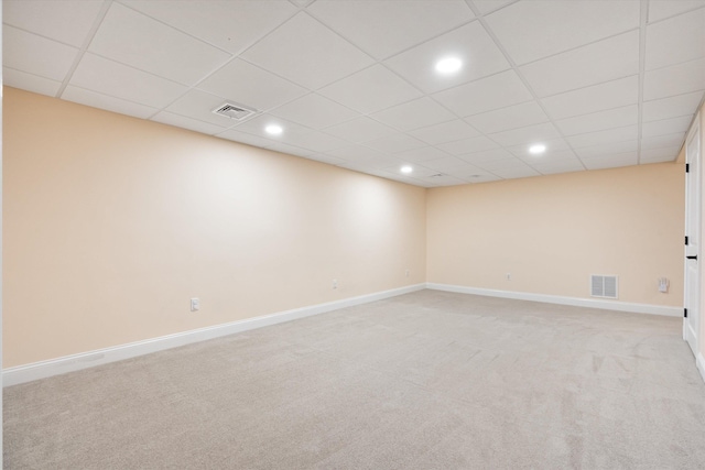 spare room featuring light colored carpet and a paneled ceiling