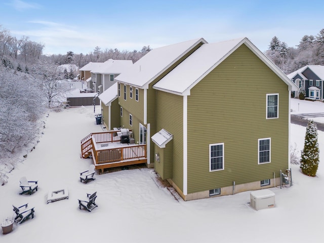 snow covered back of property with a deck