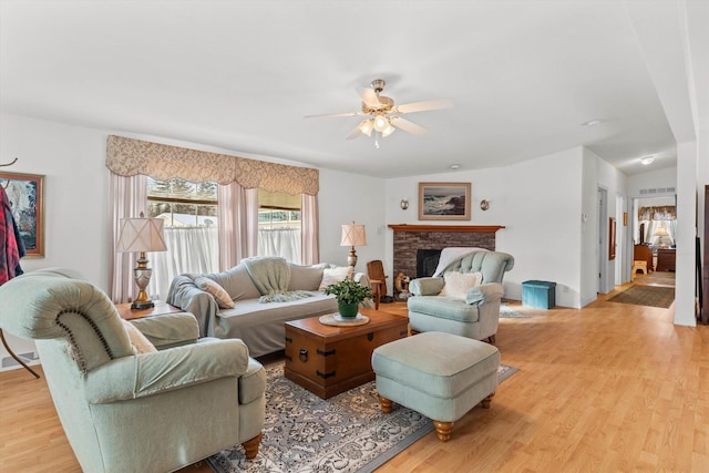 living room with ceiling fan, a fireplace, and light hardwood / wood-style floors