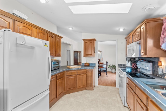 kitchen featuring sink, white appliances, and a skylight