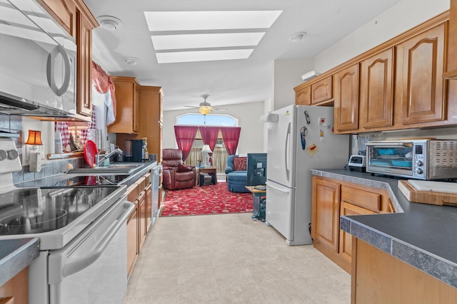 kitchen featuring ceiling fan, white appliances, and lofted ceiling with skylight