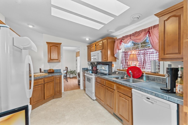 kitchen with sink, white appliances, and lofted ceiling with skylight