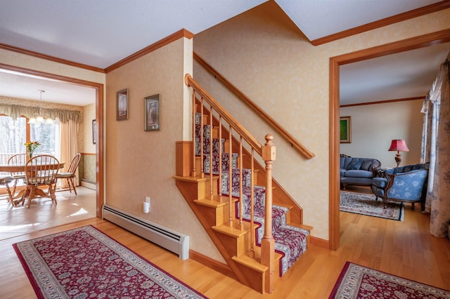 staircase featuring a baseboard radiator, ornamental molding, a chandelier, and hardwood / wood-style floors