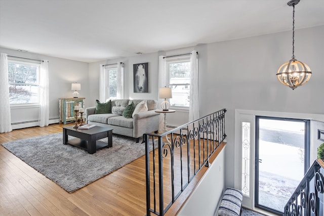 living room with hardwood / wood-style floors, a chandelier, a healthy amount of sunlight, and baseboard heating