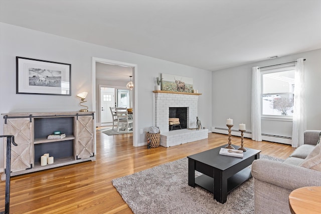 living room with a healthy amount of sunlight, wood-type flooring, a fireplace, and a baseboard radiator