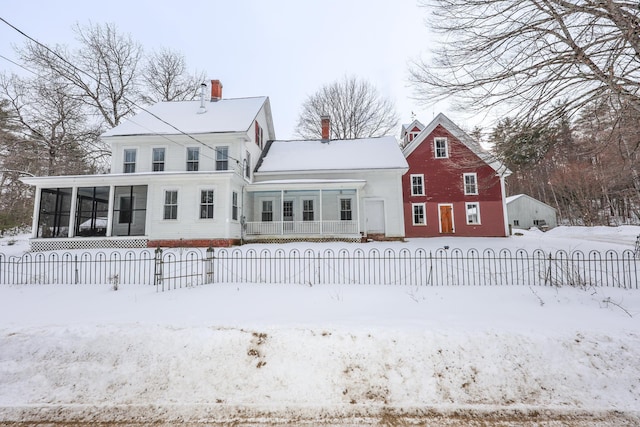 snow covered rear of property with a porch and a sunroom