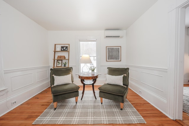 living area with wood-type flooring and an AC wall unit