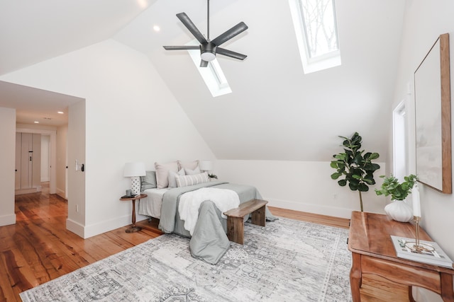 bedroom featuring ceiling fan, wood-type flooring, a skylight, and high vaulted ceiling