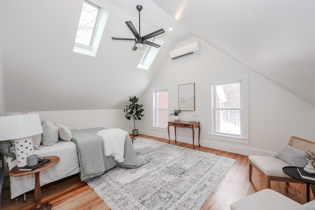 bedroom with lofted ceiling with skylight, a wall mounted air conditioner, and light wood-type flooring