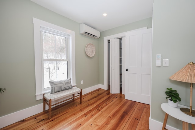 foyer with a wall unit AC and light hardwood / wood-style flooring