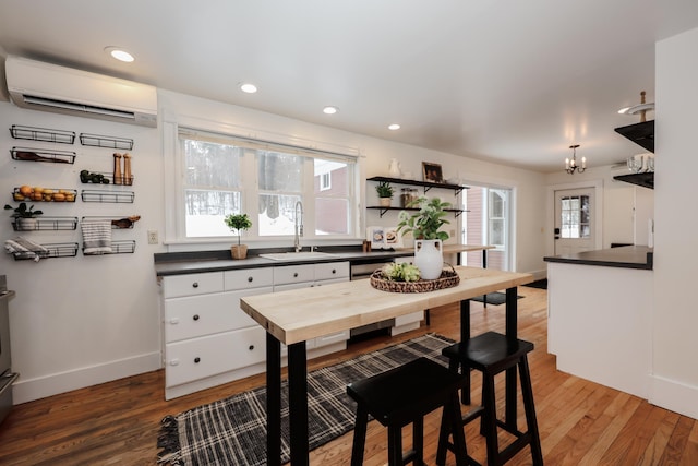 kitchen with plenty of natural light, sink, white cabinets, and a wall unit AC