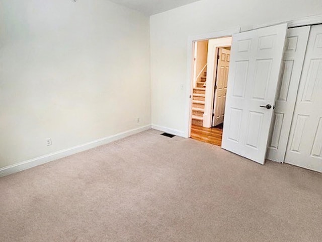 unfurnished bedroom featuring light colored carpet and a closet