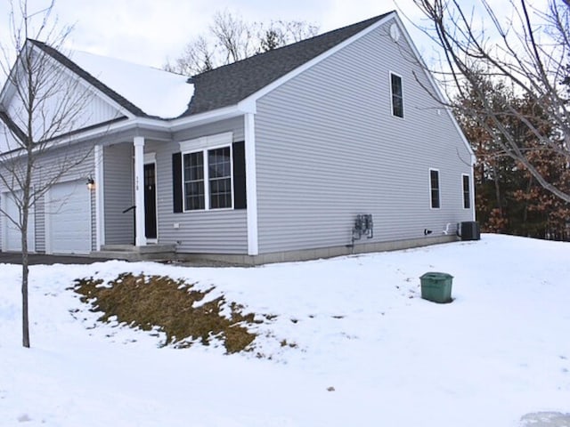 view of snow covered exterior with a garage and central AC unit