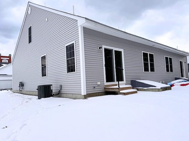 snow covered house featuring central AC unit