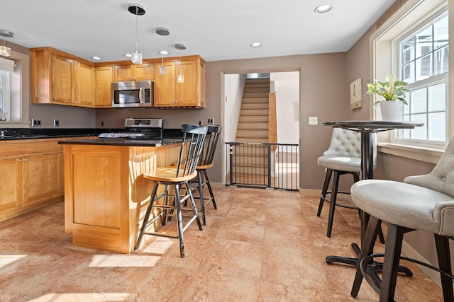 kitchen featuring a healthy amount of sunlight, stainless steel appliances, decorative light fixtures, and a kitchen bar