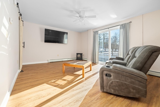 living room featuring light hardwood / wood-style floors, a barn door, ceiling fan, and baseboard heating