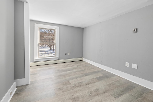 spare room with a baseboard heating unit and light wood-type flooring