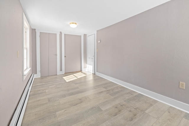 spare room featuring a baseboard radiator and light hardwood / wood-style floors