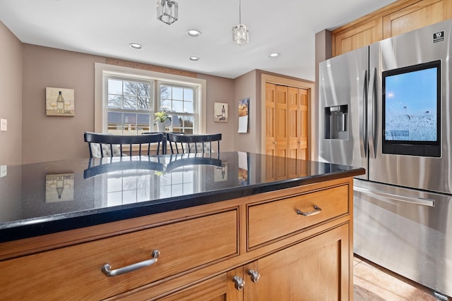 kitchen with stainless steel refrigerator with ice dispenser, dark stone counters, and pendant lighting