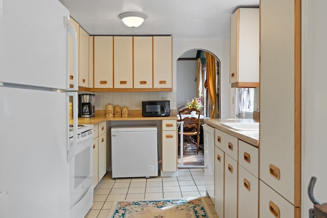 kitchen featuring white appliances, light tile patterned floors, light countertops, and decorative backsplash