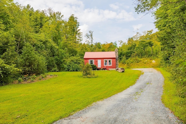 log home featuring driveway, a chimney, and a front yard