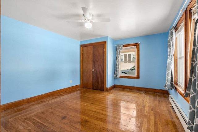 spare room with ceiling fan, a baseboard radiator, and light wood-type flooring