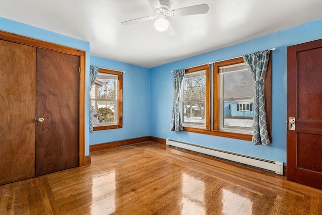 unfurnished bedroom with baseboard heating, a closet, ceiling fan, and light hardwood / wood-style flooring