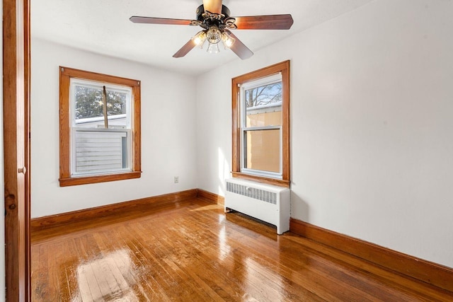 spare room with radiator, a wealth of natural light, hardwood / wood-style floors, and ceiling fan