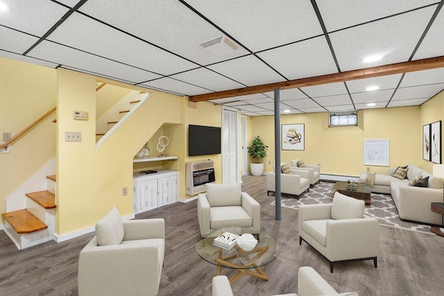 living room featuring heating unit, hardwood / wood-style floors, a baseboard radiator, and a drop ceiling