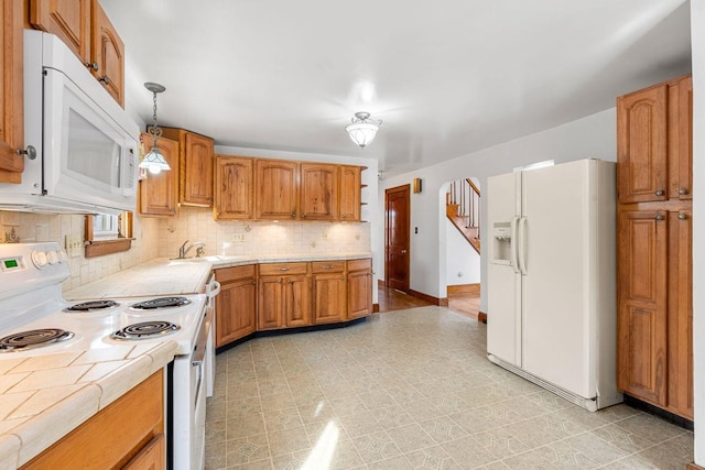 kitchen with sink, tasteful backsplash, hanging light fixtures, tile counters, and white appliances