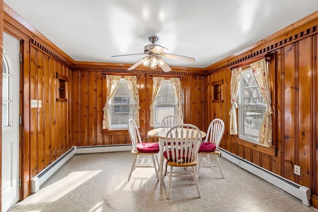 dining space featuring a baseboard radiator, wooden walls, and ceiling fan