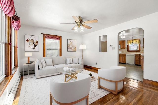 living room featuring a baseboard heating unit, ceiling fan, and light wood-type flooring