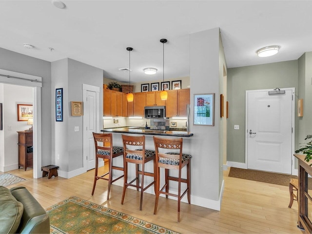 kitchen with decorative light fixtures, light hardwood / wood-style flooring, and a breakfast bar area