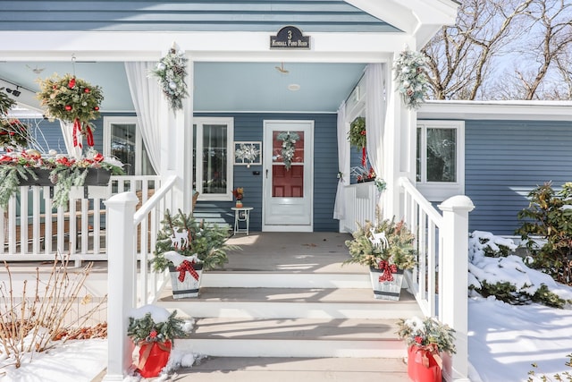 snow covered property entrance with a porch