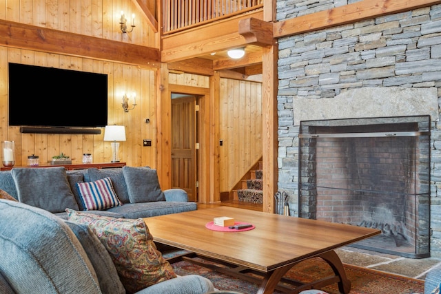 living room featuring a high ceiling, a fireplace, and wooden walls