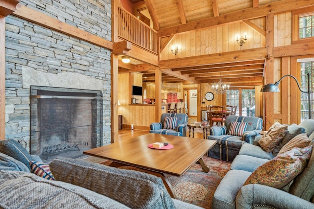 living room featuring beam ceiling, wooden walls, high vaulted ceiling, a notable chandelier, and a fireplace