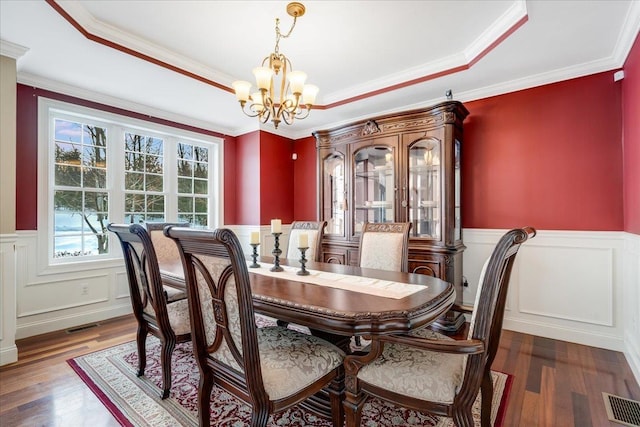 dining area featuring ornamental molding, dark hardwood / wood-style floors, an inviting chandelier, and a tray ceiling