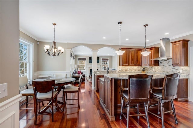 kitchen featuring pendant lighting, wall chimney exhaust hood, dark hardwood / wood-style flooring, and tasteful backsplash