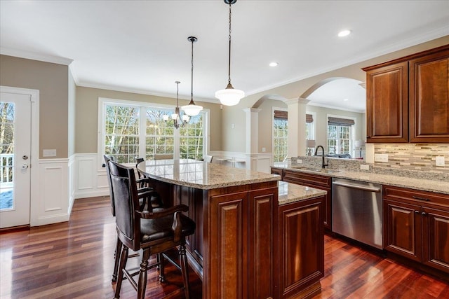 kitchen featuring sink, a breakfast bar, light stone counters, a kitchen island, and stainless steel dishwasher