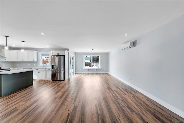 unfurnished living room with baseboards, dark wood finished floors, an AC wall unit, recessed lighting, and a sink