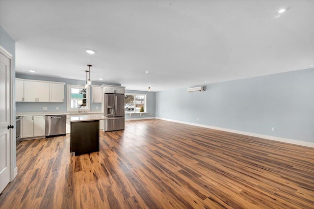 kitchen featuring a kitchen island, dark wood-type flooring, open floor plan, an AC wall unit, and appliances with stainless steel finishes