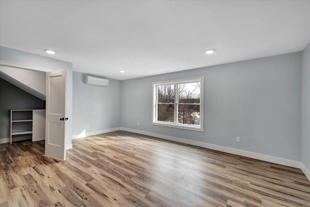 interior space featuring a wall unit AC, wood finished floors, and baseboards