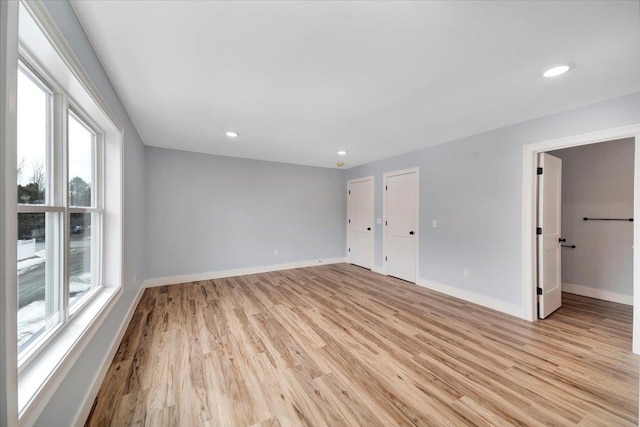 empty room featuring light wood finished floors, plenty of natural light, and baseboards