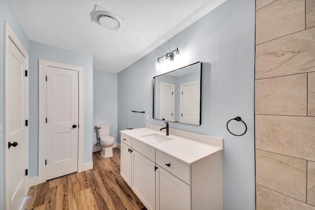 bathroom with baseboards, toilet, wood finished floors, and vanity