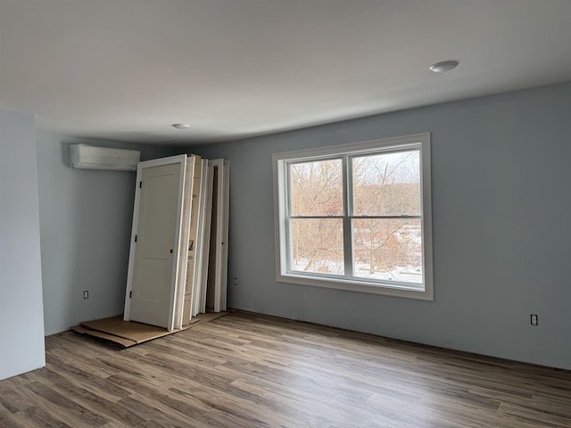 empty room featuring an AC wall unit and wood finished floors