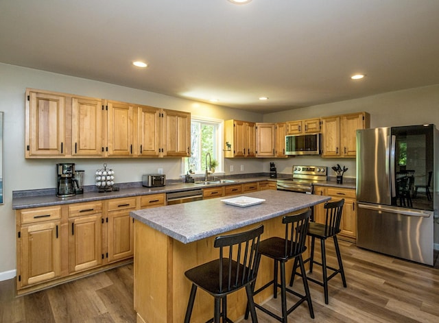 kitchen featuring sink, dark wood-type flooring, a breakfast bar, stainless steel appliances, and a center island